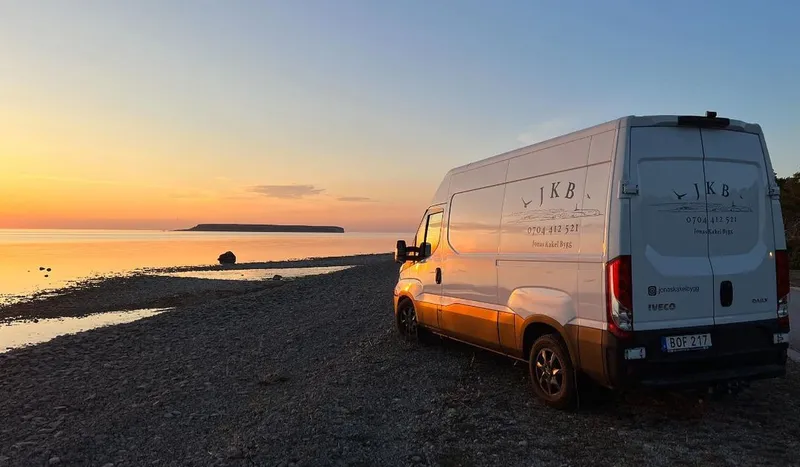 Jonas Kakel Byggs servicebil med företagsloggan vid stranden med Karlsö i bakgrunden, Gotland